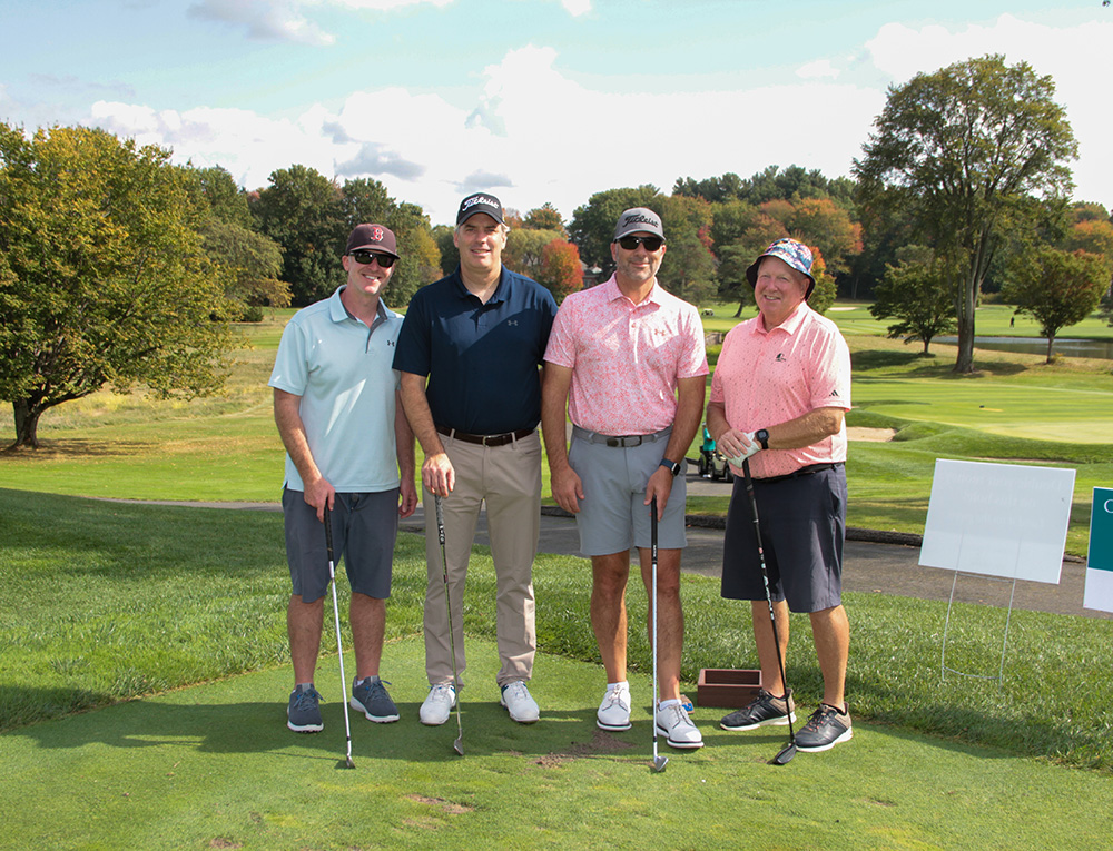Four golfers standing in front of a majestic course overview
