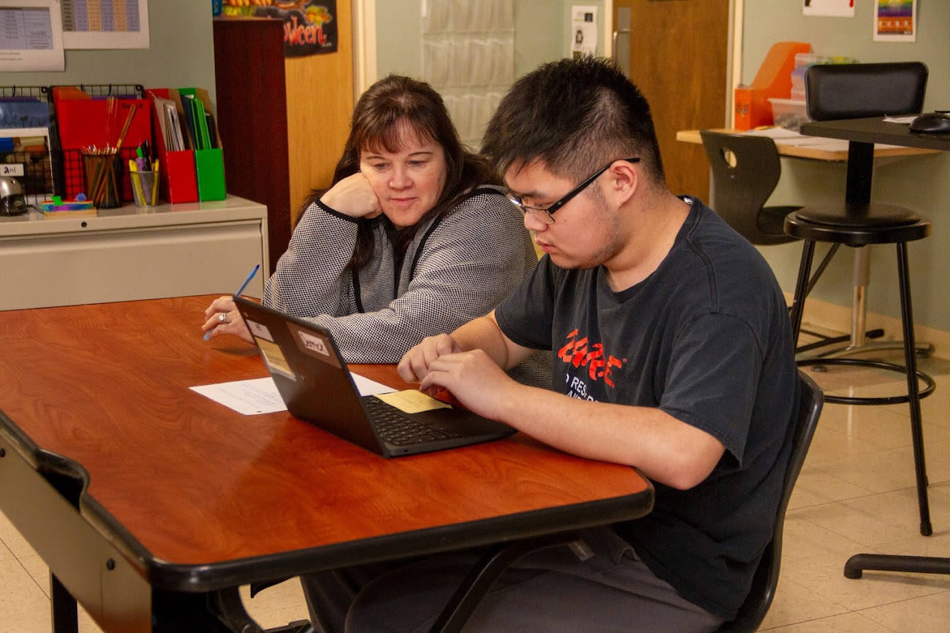 A student and teacher working on a laptop